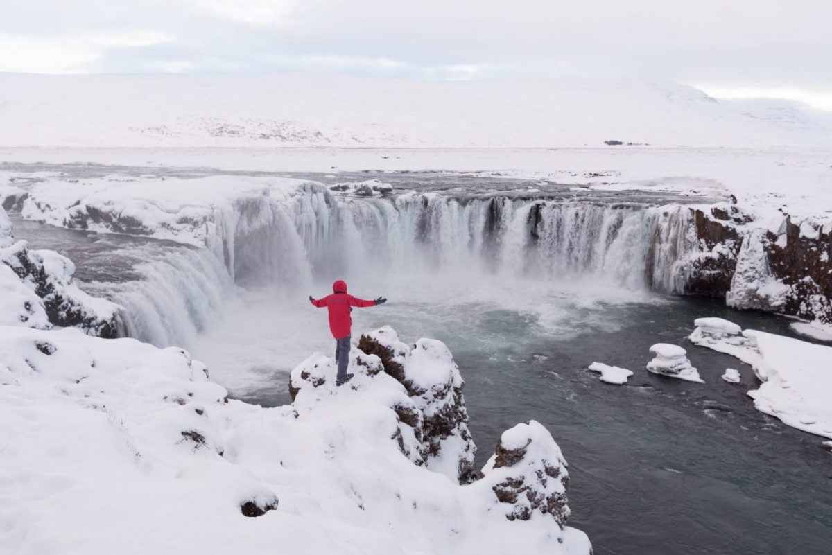 man in red standing in front of godafoss