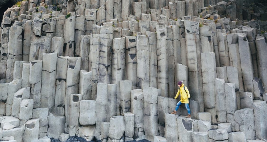 Femme marchant sur des colonnes de basalte en Islande